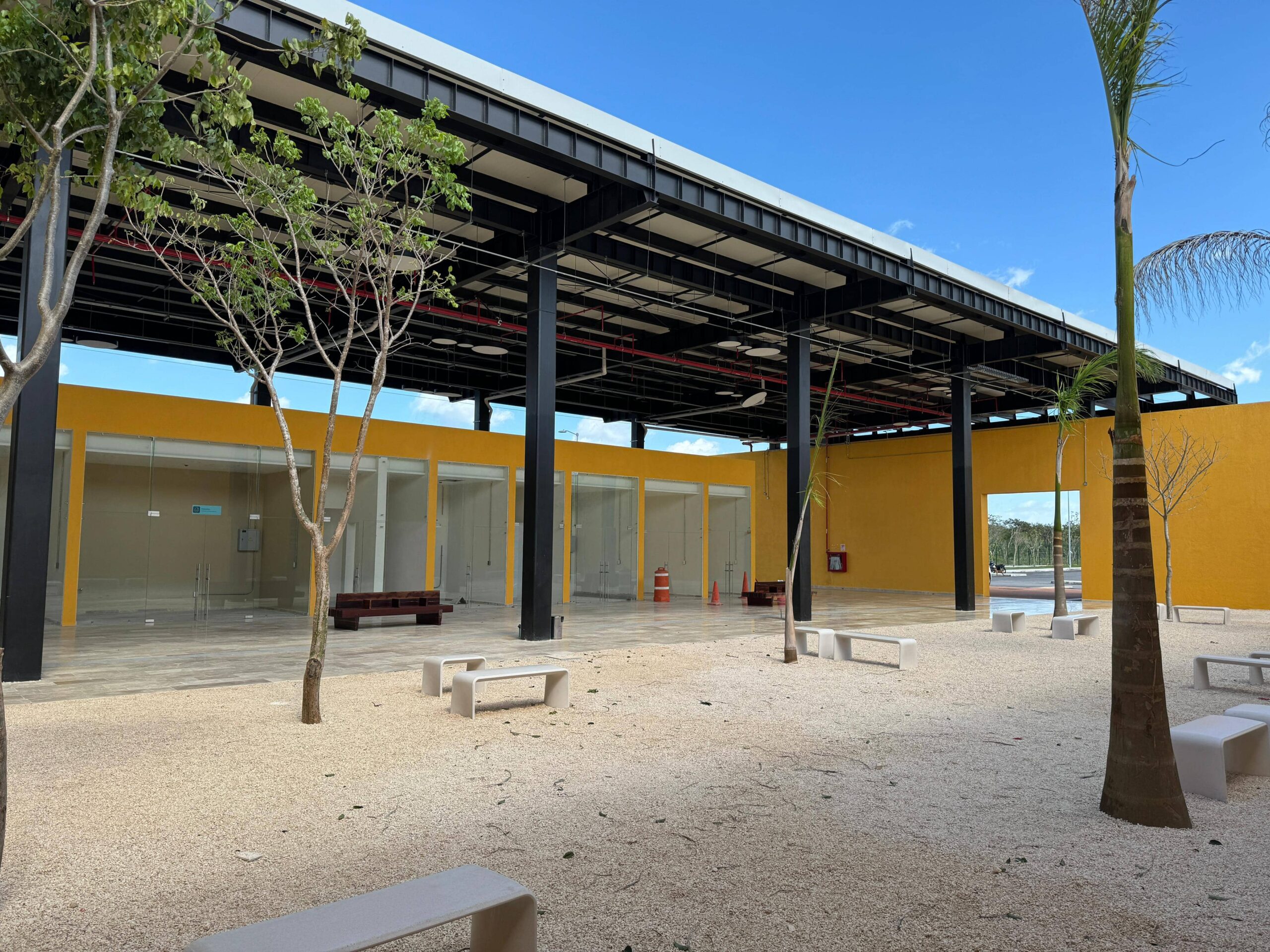 Zona de descanso con arboles y bancas en la estación de Tren Maya de Izamal
